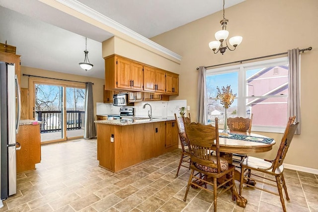 kitchen featuring a peninsula, a sink, decorative backsplash, appliances with stainless steel finishes, and brown cabinets