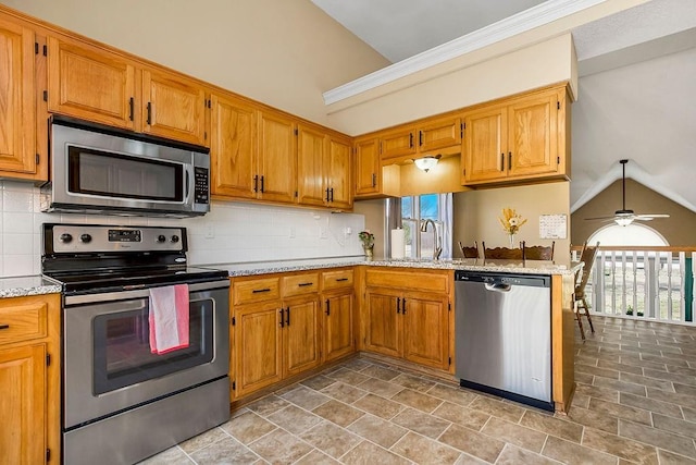 kitchen featuring light stone countertops, a sink, vaulted ceiling, appliances with stainless steel finishes, and backsplash