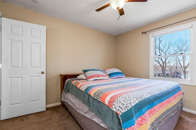 carpeted bedroom featuring multiple windows, a textured ceiling, baseboards, and a ceiling fan