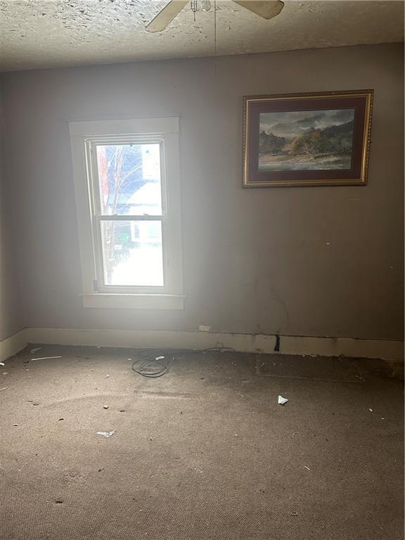 unfurnished room featuring ceiling fan and a textured ceiling