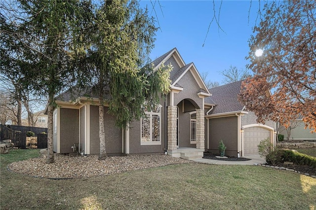 view of front of home with fence, roof with shingles, an attached garage, stucco siding, and a front lawn