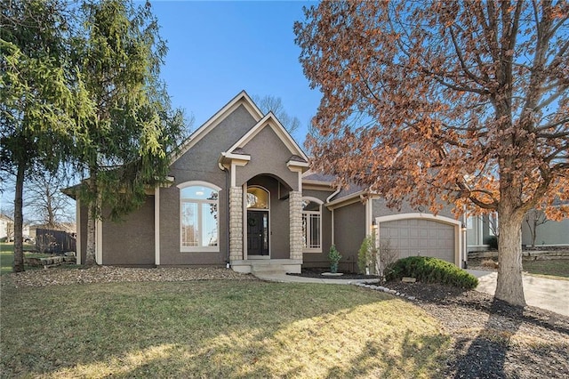 view of front facade with stucco siding, an attached garage, concrete driveway, and a front yard