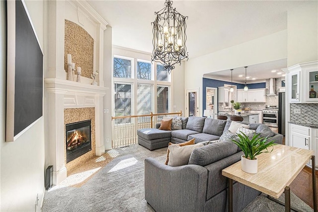 living room with a notable chandelier, a fireplace with flush hearth, and light colored carpet