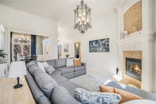 carpeted living area featuring baseboards, an inviting chandelier, and a fireplace