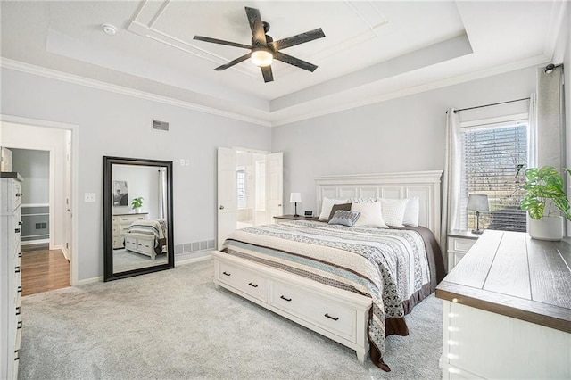 bedroom with a tray ceiling, baseboards, light colored carpet, and visible vents