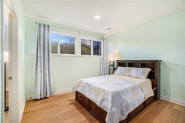 bedroom with baseboards, visible vents, and light wood finished floors