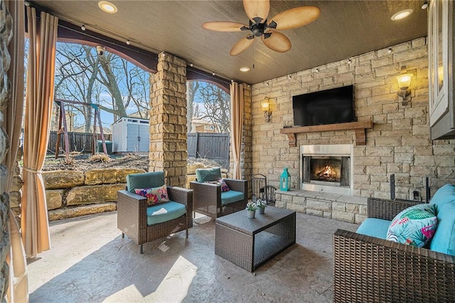 view of patio / terrace featuring a ceiling fan, fence, an outdoor living space with a fireplace, an outdoor structure, and a storage unit