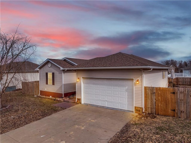 ranch-style home featuring concrete driveway, roof with shingles, fence, and an attached garage