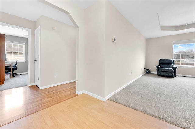 unfurnished room with arched walkways, a healthy amount of sunlight, baseboards, and wood finished floors