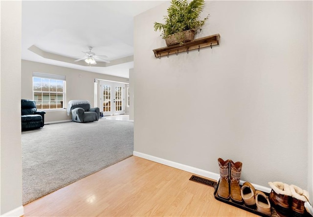 hallway with french doors, visible vents, carpet flooring, wood finished floors, and baseboards