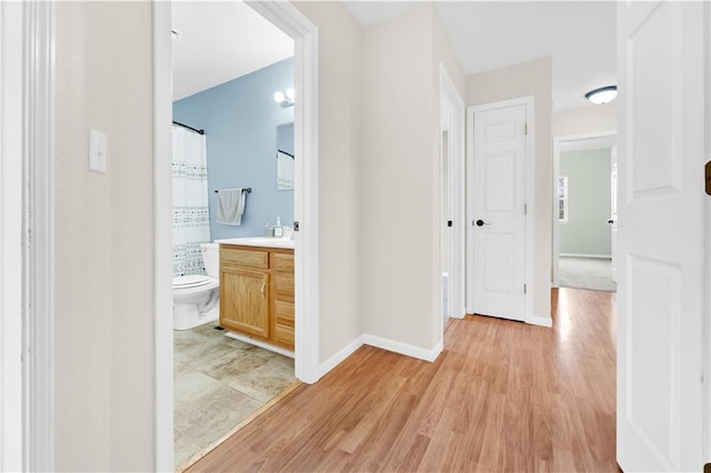 hallway with light wood-style floors and baseboards