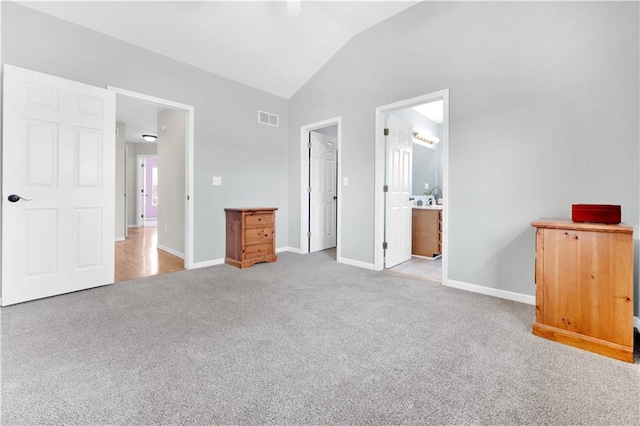 unfurnished bedroom featuring ensuite bathroom, lofted ceiling, light carpet, visible vents, and baseboards