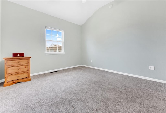 unfurnished room featuring baseboards, visible vents, vaulted ceiling, and carpet flooring