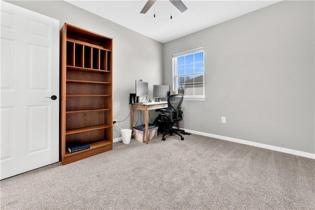 carpeted office space featuring a ceiling fan and baseboards