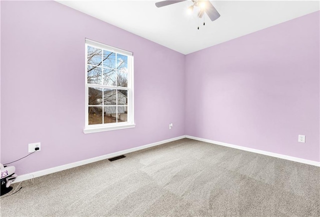 carpeted empty room with baseboards, visible vents, and a ceiling fan