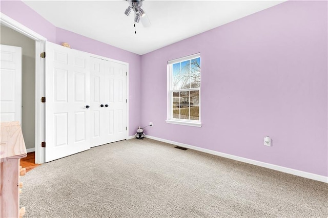 unfurnished bedroom with ceiling fan, carpet floors, visible vents, baseboards, and a closet