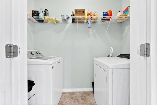 clothes washing area with laundry area, tile patterned floors, washing machine and clothes dryer, and baseboards