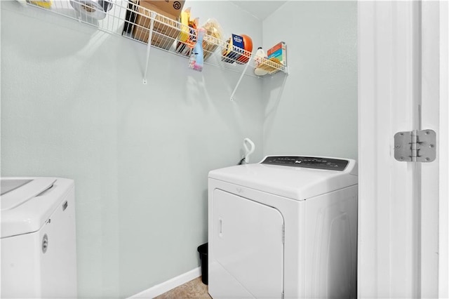 laundry area featuring laundry area, baseboards, and washing machine and clothes dryer