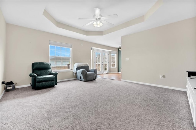 living area featuring baseboards, a ceiling fan, a tray ceiling, carpet flooring, and french doors