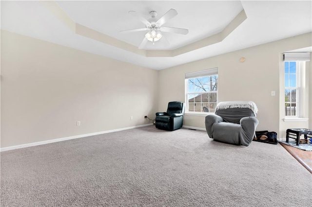 sitting room featuring ceiling fan, carpet, baseboards, and a raised ceiling