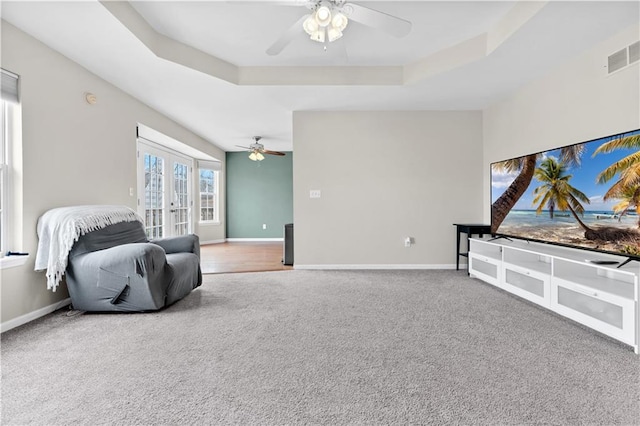 living area with carpet floors, a tray ceiling, french doors, and baseboards