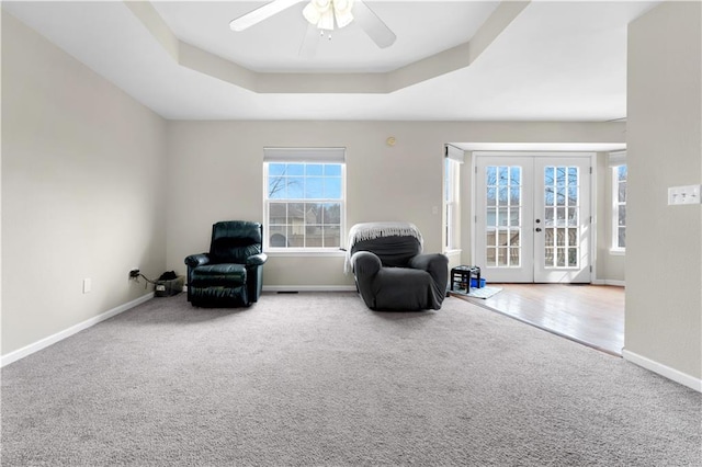 sitting room with carpet floors, a tray ceiling, french doors, and baseboards