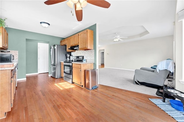 kitchen with under cabinet range hood, tasteful backsplash, appliances with stainless steel finishes, and light countertops