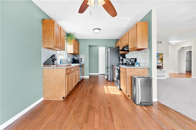 kitchen featuring baseboards, stainless steel appliances, light countertops, and decorative backsplash