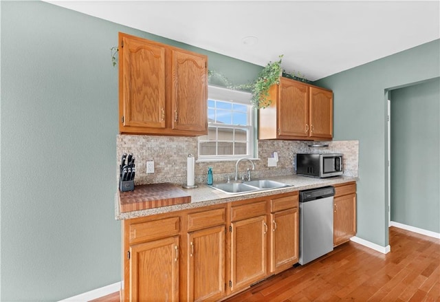 kitchen featuring stainless steel appliances, light countertops, a sink, and decorative backsplash