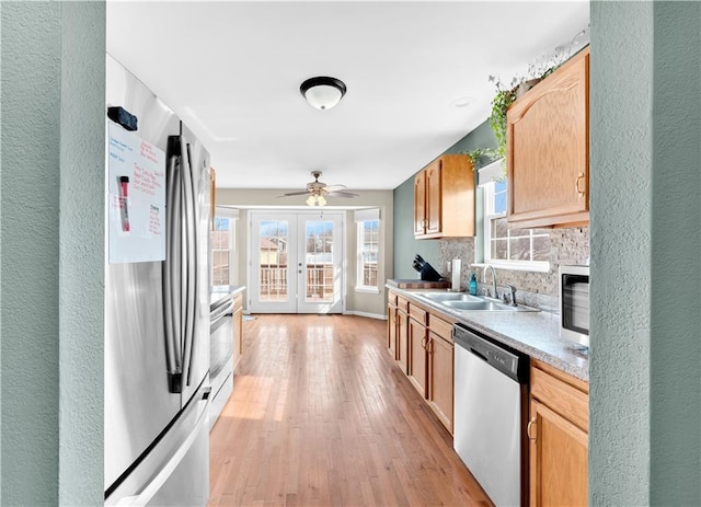 kitchen with decorative backsplash, light wood-style flooring, stainless steel appliances, french doors, and a sink