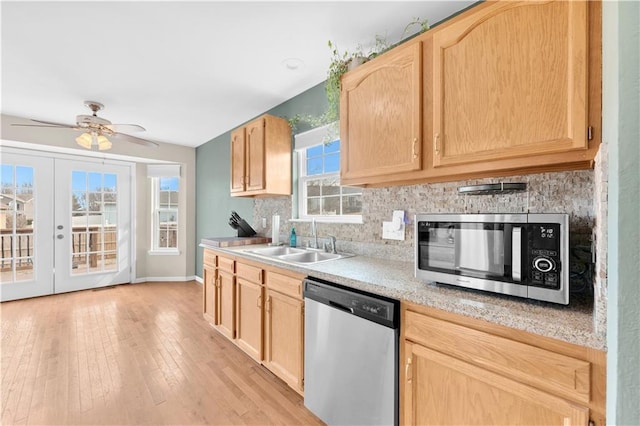 kitchen with appliances with stainless steel finishes, a sink, light countertops, light brown cabinets, and backsplash