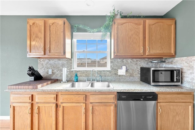 kitchen with stainless steel appliances, a sink, light countertops, light brown cabinetry, and tasteful backsplash