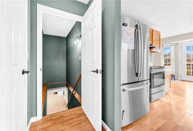 kitchen with appliances with stainless steel finishes, light wood-style flooring, and baseboards