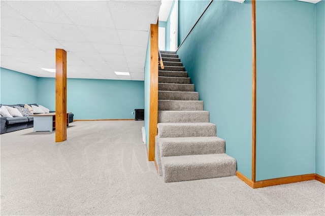 staircase with carpet floors, baseboards, and a paneled ceiling