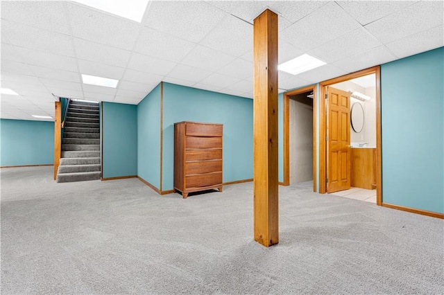 finished below grade area featuring carpet floors, baseboards, stairway, and a paneled ceiling