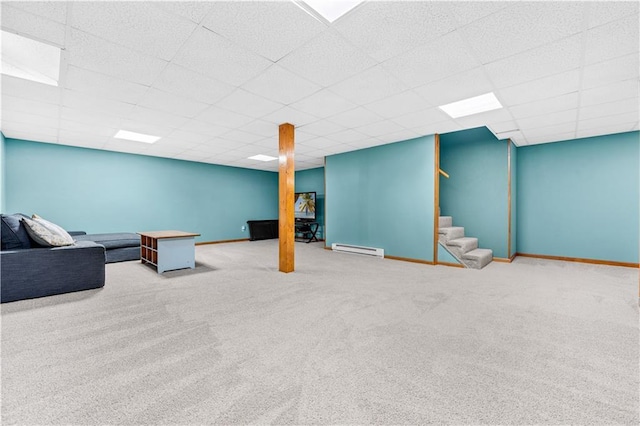 finished basement featuring a baseboard radiator, a paneled ceiling, stairway, and baseboards