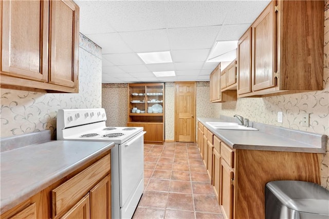 kitchen with a drop ceiling, electric range, a sink, light countertops, and wallpapered walls