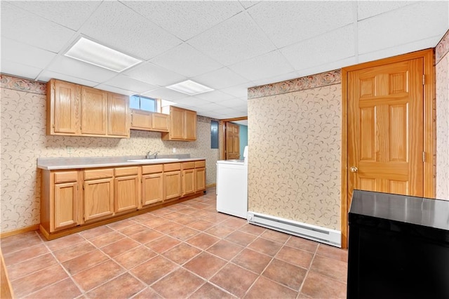 kitchen with a paneled ceiling, a baseboard heating unit, a sink, light countertops, and washer / dryer