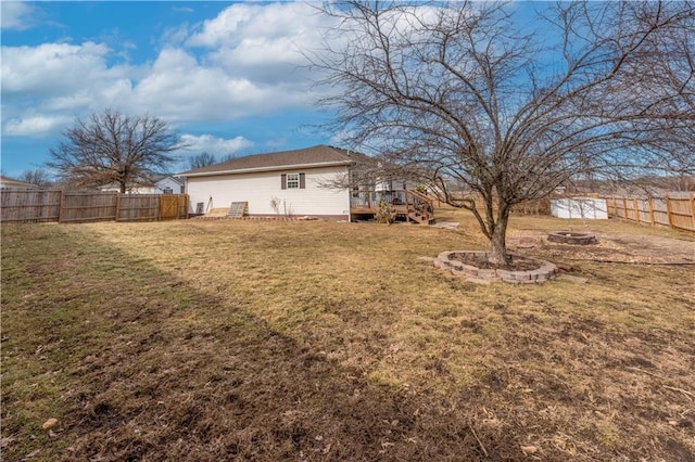 view of yard with an outbuilding, a storage unit, a deck, a fenced backyard, and a fire pit