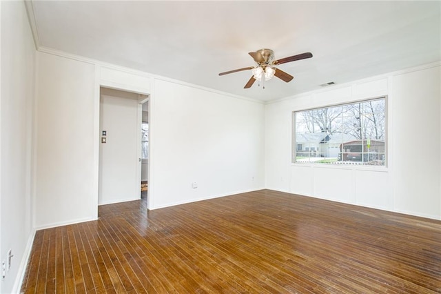 spare room with visible vents, crown molding, dark wood-style floors, a decorative wall, and a ceiling fan