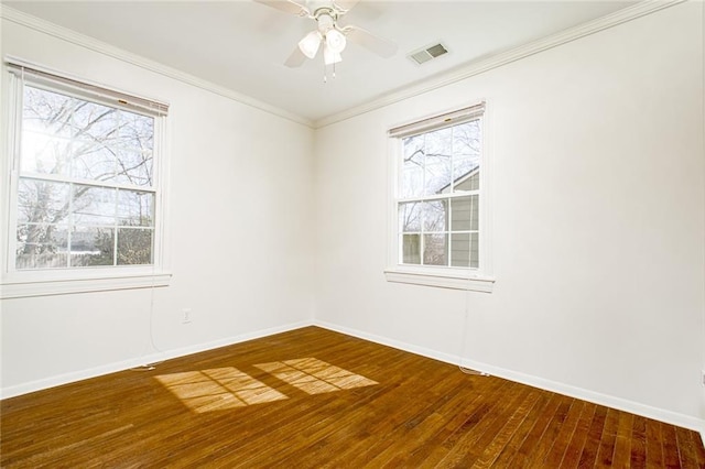 empty room with baseboards, wood finished floors, visible vents, and ornamental molding