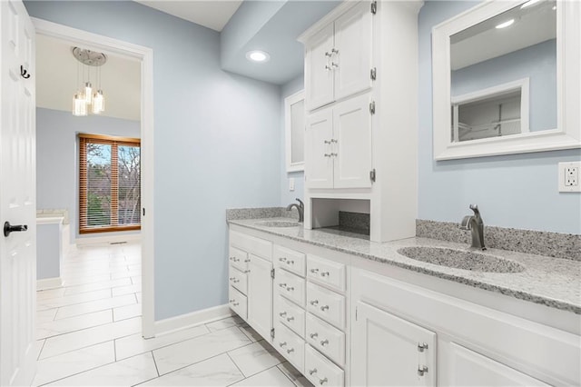 full bathroom with a sink, baseboards, marble finish floor, and double vanity