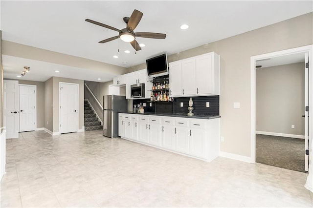 kitchen with baseboards, stainless steel appliances, white cabinetry, dark countertops, and backsplash