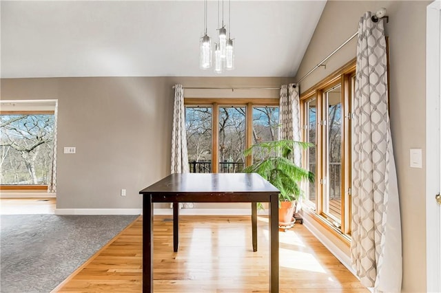 unfurnished dining area with baseboards, light wood-style floors, and vaulted ceiling