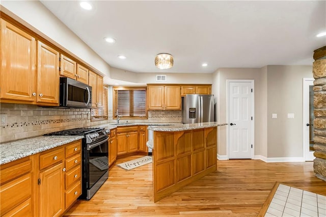 kitchen featuring visible vents, a center island, light wood-style flooring, appliances with stainless steel finishes, and a sink