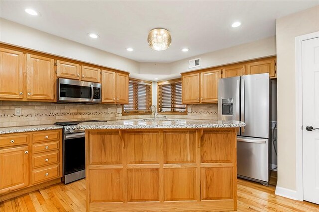 kitchen featuring light wood finished floors, visible vents, appliances with stainless steel finishes, and a sink