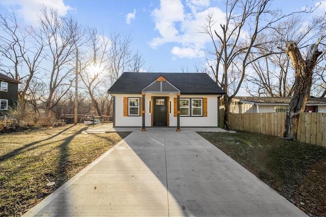 bungalow-style home featuring a shingled roof and fence