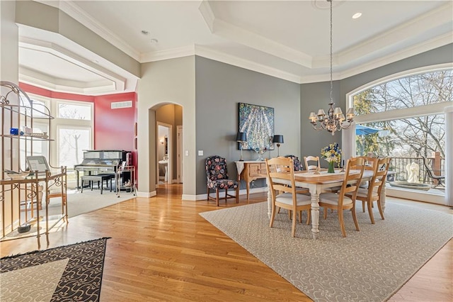 dining space featuring a tray ceiling, wood finished floors, visible vents, and arched walkways