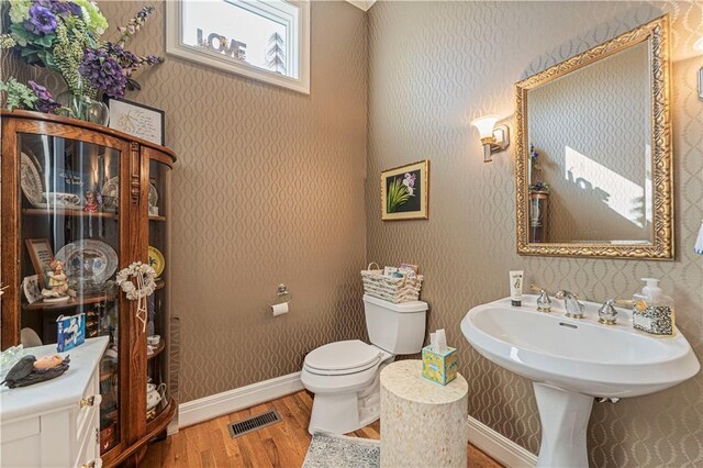 bathroom featuring wallpapered walls, toilet, wood finished floors, and visible vents