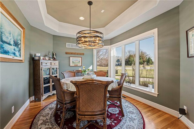 dining area featuring baseboards, visible vents, light wood finished floors, a tray ceiling, and a notable chandelier